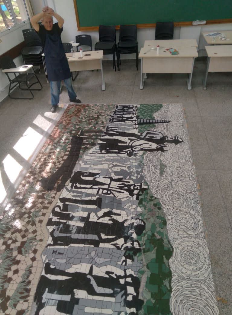 Javier Guerrero diante de um grande painel em mosaico em espaco de formacao.